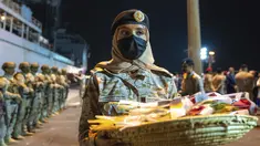 Nour Al-Ghanmi dari Angkatan Laut Kerajaan Arab Saudi membawa nampan berisi permen untuk menyambut warga yang dievakuasi dari Sudan di Pelabuhan Jeddah, Arab Saudi, Senin (24/4/2023). ( Saudi Ministry of Media via AP)
