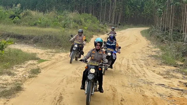 Kapolsek Tapung Kompol Nur Syafniati memakai sepeda motor untuk sosialisasikan Pilkada damai.