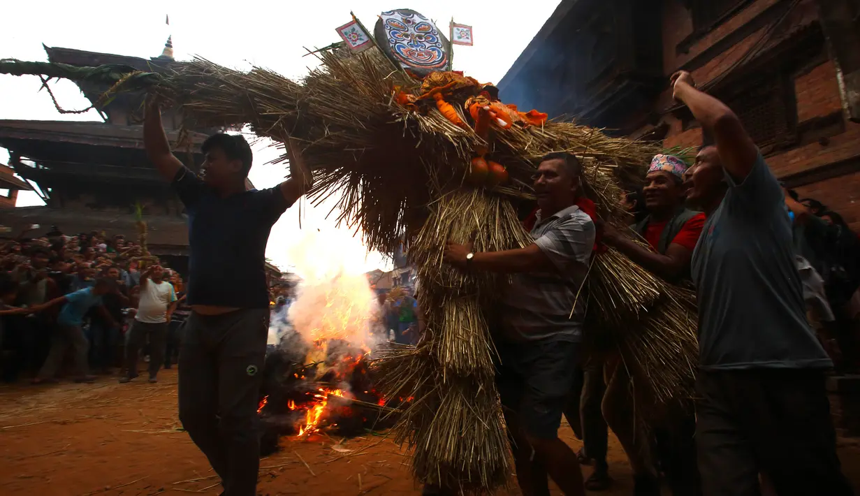 Umat Hindu Nepal membawa jerami untuk dibakar dalam perayaan Ghanta Karna di Bhaktapur di pinggiran Kathmandu, Nepal (21/7). Ritual ini untuk merayakan kekalahan iblis dalam mitos Ghanta Karna. (AFP Photo/Gopen Rai)
