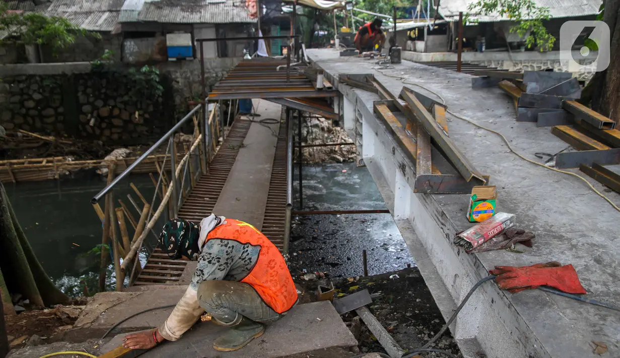 Pekerja menyelesaikan proyek pembangunan jembatan penghubung antarkampung di kawasan Pondok Pinang, Jakarta, Jumat (13/12/2019).  Jembatan yang menghubungkan permukiman di daerah Pondok Pinang dengan kawasan Bintaro tersebut ditargetkan rampung pada akhir Desember. (Liputan6.com/Faizal Fanani)