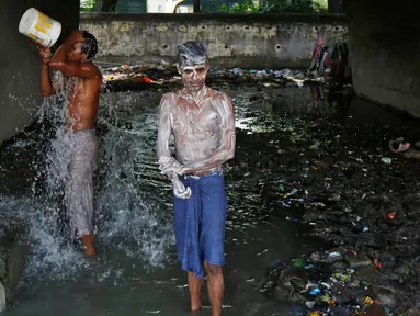 Dua laki-laki mandi di bawah sebuah jembatan di daerah kumuh di Kalkuta, India (26/5/2016). Kalkuta adalah salah satu kota pelabuhan penting di India yang merupakan ibu kota Benggala Barat. (REUTERS/Rupak De Chowdhuri)