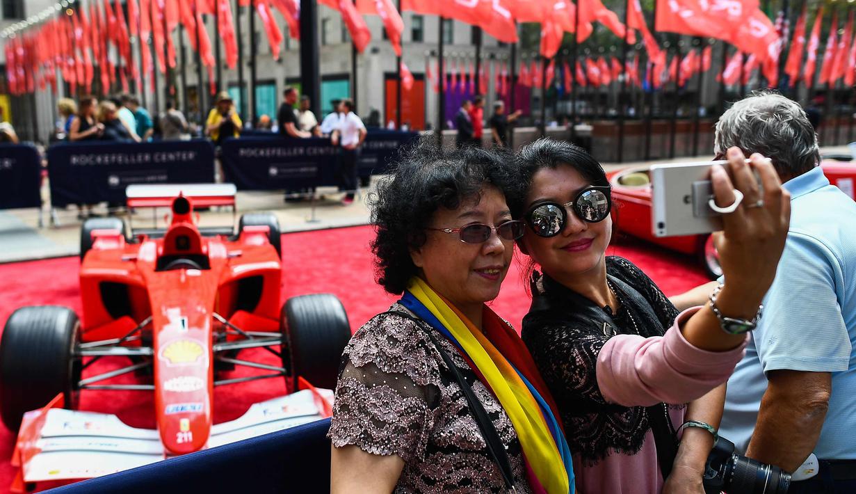 Dua wanita berselfie dengan latar mobil mantan pembalap Ferrari F1, Michael Schumacher di Rockefeller Plaza, New York, AS (8/10). Mobil tersebut pernah memenangkan salah satu seri balapan F1 di Grand Prix Monaco pada tahun 2001. (AFP Photo/Jewel Samad)