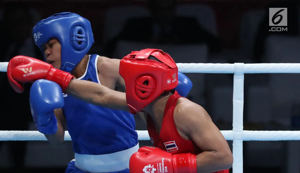 Petinju putri Indonesia, Huswatun Hasanah (kaus biru) menerima pukulan dari Sudaporn Seesondee (Thailand) pada semifinal kelas ringan 60kg putri Asian Games 2018 di JIEXPO Kemayoran, Jumat (31/8). Huswatun kalah. (Liputan6.com/Helmi Fithriansyah)