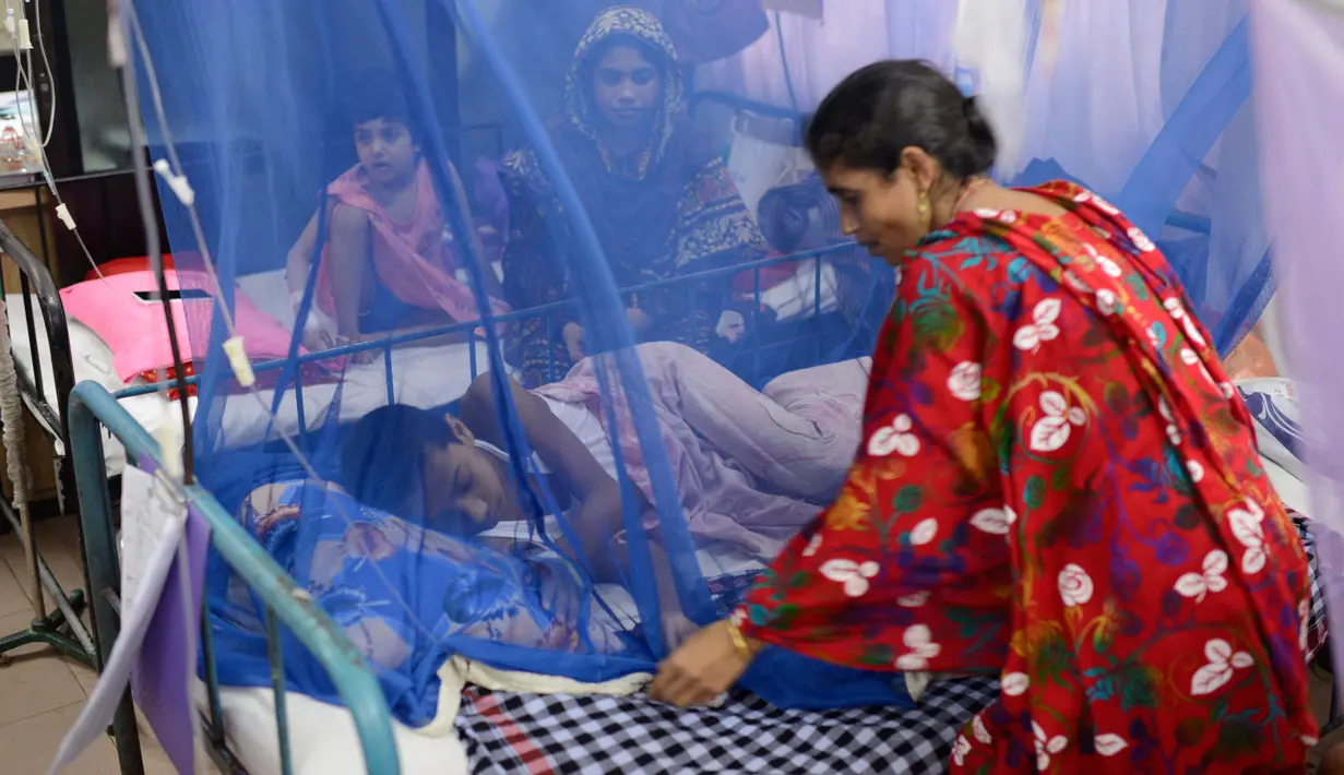 Seorang wanita merapikan tempat tidur anaknya yang menjadi pasien demam berdarah di Rumah Sakit Shishu Dhaka, Bangladesh, Rabu (31/7/2019). Banyak rumah sakit dibanjiri pasien penyakit itu sehingga semakin membebani sistem layanan medis yang saat ini sudah kewalahan. (AP Photo/Mahmud Hossain Opu)