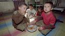 Anak-anak makan nasi di sebuah kamar di panti asuhan terakhir yang tersisa di Kabul, Afghanistan, 26 Oktober 1996. Ratusan anak menghadapi pertempuran untuk bertahan hidup setelah pemimpin baru Taliban di Kabul melarang perempuan bekerja dan memotong dana untuk panti asuhan. (SAEED KHAN/AFP)