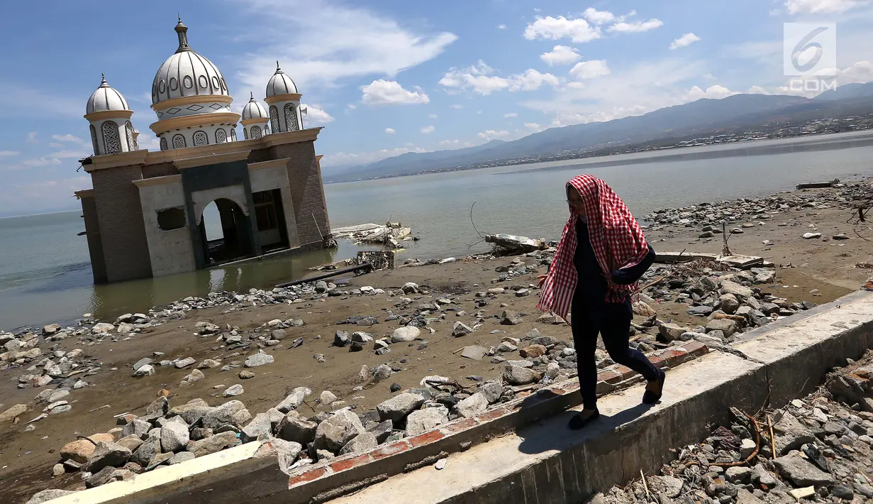 Warga melintas di depan Masjid Terapung Arqam Bab Al Rahman pasca gempa dan tsunami Palu di Pantai Talise, Sulawesi Tengah. Masjid yang dibangun tahun 2011 awalnya menampung 150 jamaah. (Liputan6.com/Fery Padolo)
