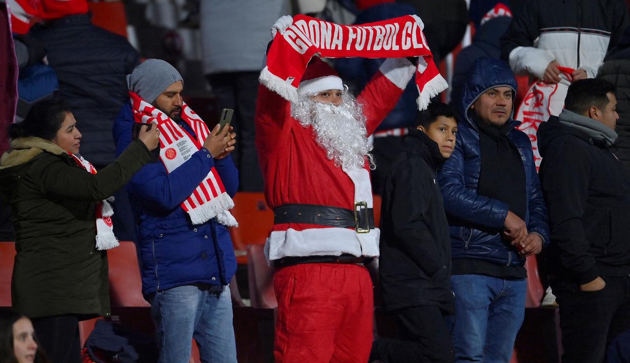 Seorang pendukung Girona dengan mengenakan busana Santa Claus merayakan kemenangan timnya atas Alaves setelah berakhirnya laga pekan ke-17 Liga Spanyol 2023/2024 di Montilivi Stadium, Girona, Selasa (19/12/2023) dini hari WIB. (AFP/Pau Barrena)