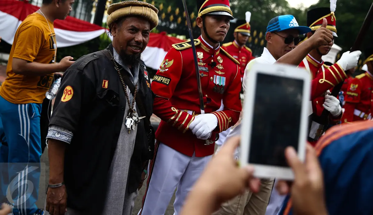 Warga berfoto bersama anggota Paspampres yang melakukan prosesi pergantian jaga Istana Kepresiden di depan Istana Merdeka, Minggu (28/8). Prosesi pergantian yang diwarnai sejumlah atraksi itu mengundang perhatian warga. (Liputan6.com/Faizal Fanani)