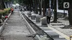 Pejalan kaki melintas saat pekerja menyelesaikan proyek revitalisasi pedestrian di kawasan Jalan Pattimura, Jakarta, Rabu (8/6/2022). Dinas Bina Marga DKI Jakarta merevitalisasi pedestrian dengan memperlebar menjadi tiga meter sehingga cukup luas untuk memberikan kenyamanan para pejalan kaki. (Liputan6.com/Faizal Fanani)