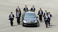 Para pengawal berlari di samping mobil yang membawa Pemimpin Korea Utara Kim Jong-un saat akan makan siang dalam KTT Korea Selatan-Korea Utara di zona demiliterisasi, Panmunjom, Korea Selatan, Jumat (27/4). (Korea Summit Press Pool/AFP)
