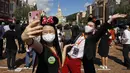 Disneyland Hong Kong Kembali Dibuka: Para pengunjung yang mengenakan masker untuk mencegah penyebaran COVID-19 berswafoto di Disneyland Hong Kong, Kamis (18/6/2020). Disneyland Hong Kong kembali beroperasi pada 18 Juni 2020 dengan menerapkan sejumlah protokol kesehatan baru. (AP Photo/Kin Cheung)