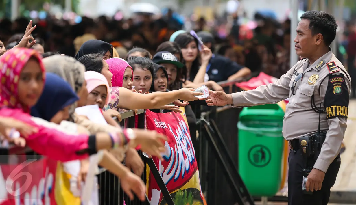 Petugas keamanan memberikan minum kepada peserta yang mengantri Audisi D Academy 3 Indosiar di Jakarta, (6/12). Tak hanya dari Jakarta, peserta juga berasal dari berbagai daerah seperti Papua dan beberapa kota di Sumatera. (Liputan6.com/Faizal Fanani)
