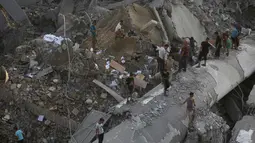 Warga melihat puing-puing bangunan yang hancur akibat serangan udara Israel di Kota Gaza, Palestina, (9/8). Tentara Israel kembali membombardir Gaza sebagai aksi balasan terhadap serangan militan Hamas. (AP Photo/Khalil Hamra)