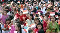 Ratusan anak-anak mengibarkan bendera Merah Putih saat gelaran Harmoni Indonesia 2018 di Kompleks Gelora Bung Karno, Jakarta, Minggu (5/8). Presiden RI, Joko Widodo hadir dalam acara tersebut. (Liputan6.com/Helmi Fithriansyah)