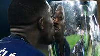 Pemain PSG, Ousmane Dembele, mencium trofi Piala Super Eropa 2025 setelah mengalahkan Tottenham Hotspur pada laga final, Kamis (14/8/2025) dini hari WIB. (Marco BERTORELLO / AFP)