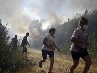 Orang-orang berlari untuk menyelamatkan diri dari api kebakaran hutan di dekat desa Melon, Spanyol barat laut, pada 17 Agustus 2025. (MIGUEL RIOPA/AFP)