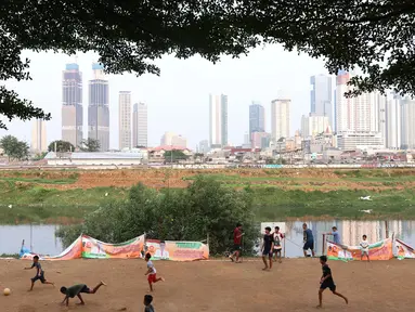 Sejumlah anak asyik bermain sepak bola di bantaran kali Banjir Kanal Barat (BKB), Jakarta. Minimnya lahan bermain tak menyurutkan semangat mereka untuk berolahraga sekaligus bersenang-senang dengan sepak bola. (bola.com/M Iqbal Ichsan)