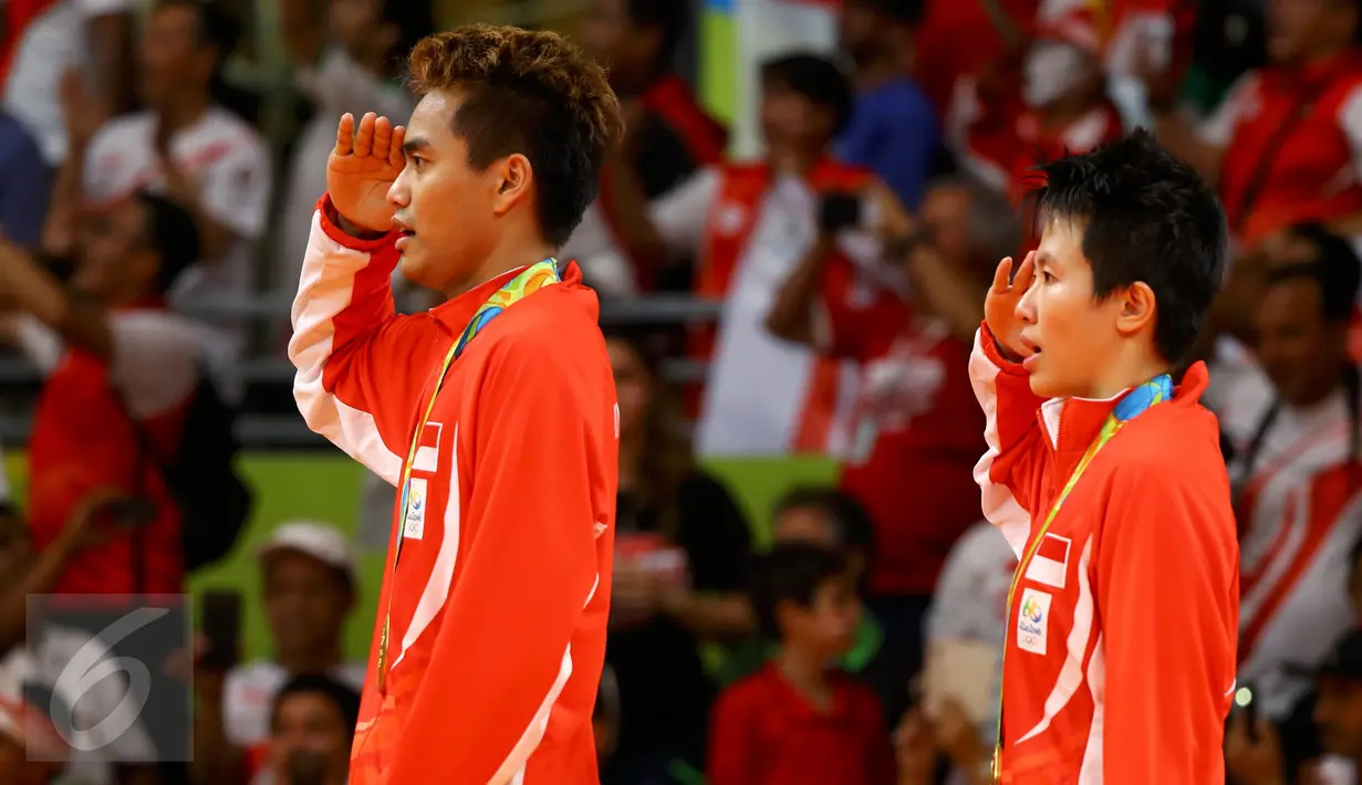 Pasangan ganda campuran Indonesia, Tontowi Ahmad dan Liliyana Natsir memberikan hormat saat menyanyikan lagu Indonesia Raya usai mengalahkan lawannya asal Malaysia Peng Soon Chan dan Liu Ying Goh pada final bulutangkis di, Brasil. (REUTERS/Mike Blake)