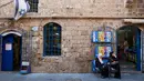 Dua wanita duduk di depan sebuah toko di pelabuhan Jaffa, Israel,  21 Juli 2018. Jaffa merupakan pelabuhan tertua di dunia. (AP Photo/Oded Balilty)