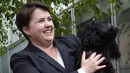 Pimpinan partai Konservatif Skotlandia, Ruth Davidson berpose bersama anjingnya di luar kafe yang dijadikan TPS di Edinburgh, Kamis (8/6). Para pemilih mengajak anjingnya untuk menemani mereka mengambil bagian dalam Pemilu Inggris. (Lesley Martin/AFP)
