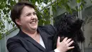 Pimpinan partai Konservatif Skotlandia, Ruth Davidson berpose bersama anjingnya di luar kafe yang dijadikan TPS di Edinburgh, Kamis (8/6). Para pemilih mengajak anjingnya untuk menemani mereka mengambil bagian dalam Pemilu Inggris. (Lesley Martin/AFP)