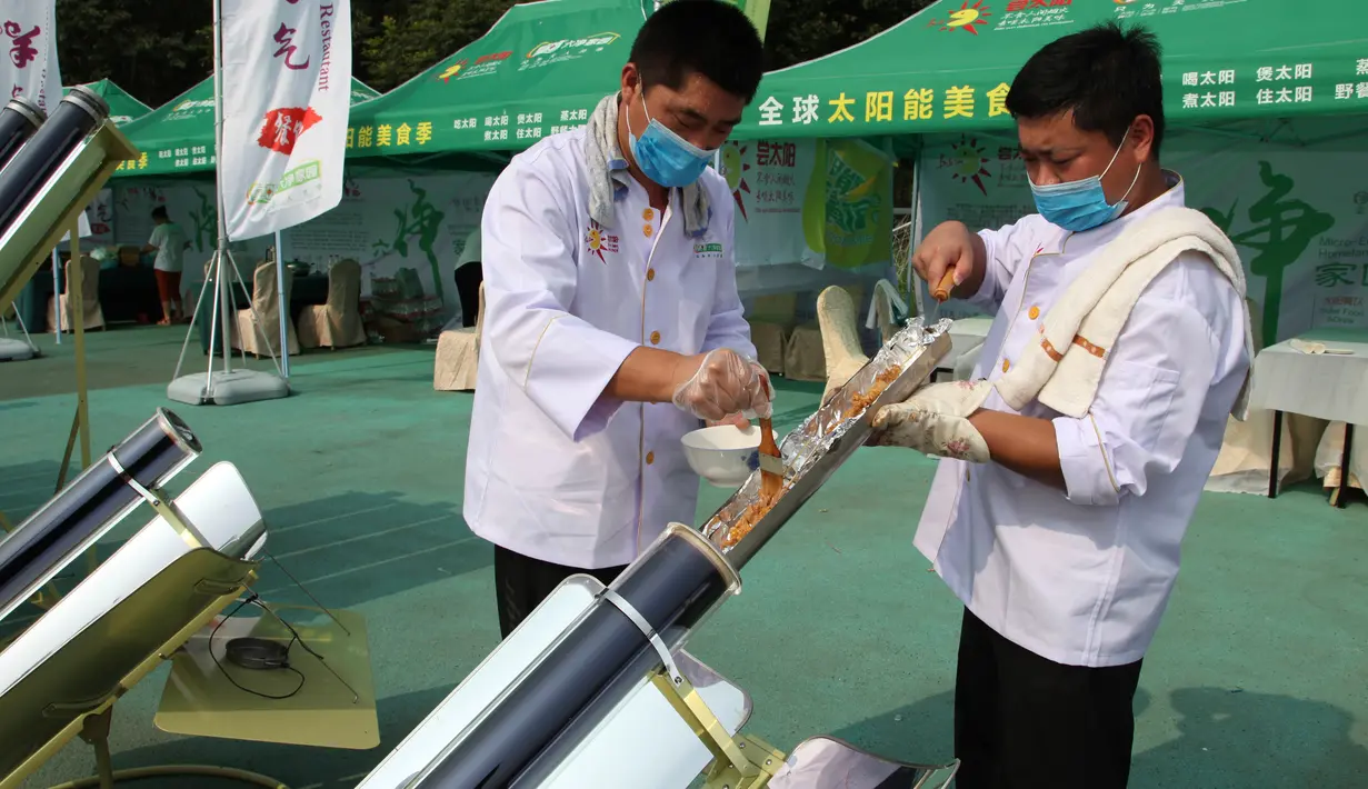 Dua koki memasukkan daging sate ke dalam tabung logam dan dimasak menggunakan kompor tenaga surya di Dezhou, Shandong Timur, Cina, 2 Agustus 2018. Koki memasak pada festival masak menggunakan kompor tenaga surya di Cina. (AP Foto/Fu Ting)