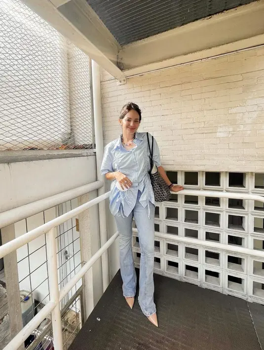 Kemeja berwarna biru muda dengan aksen tali serut pada bagian kanan dan kiri sangat ciamik dipasangkan dengan jeans berwarna senada sebagai outfit work from officemu, lho. (instagram/enzystoria)