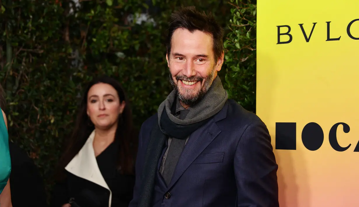 Bintang John Wick, 59, itu mengenakan setelan gelap dengan syal dan sepatu bot cokelat. (Momodu Mansaray/Getty Images/AFP)