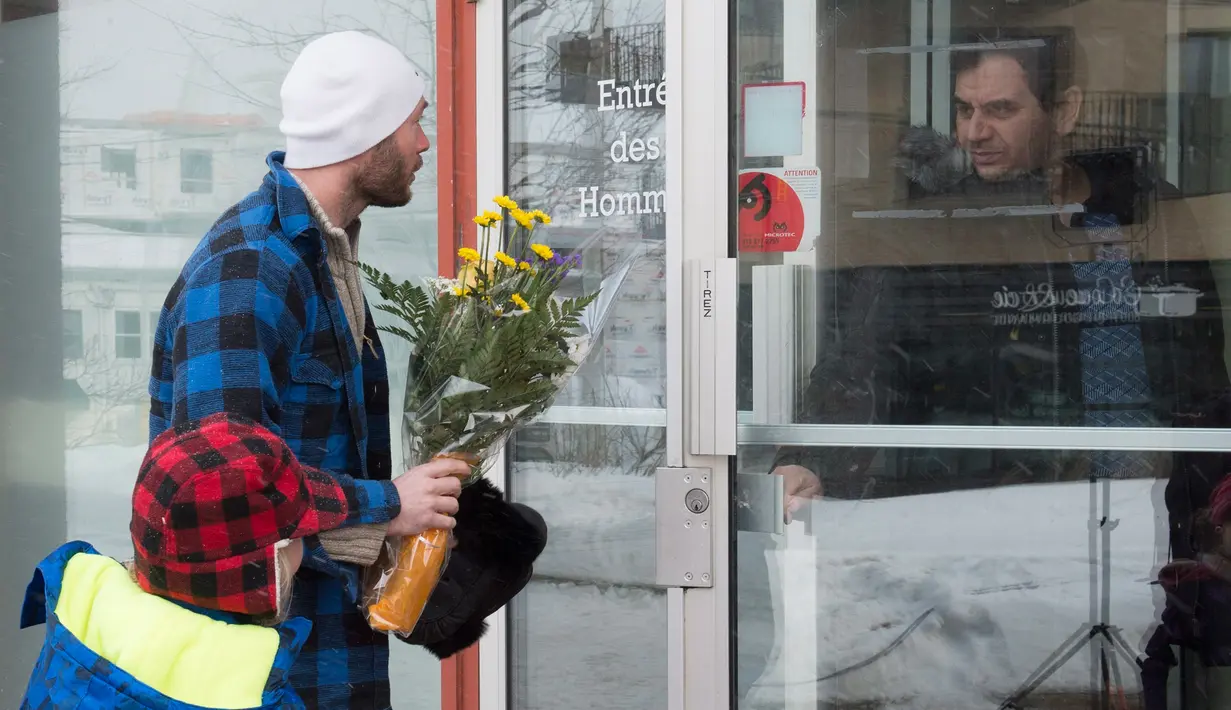 Seorang pria bersama anaknya membawa bunga untuk diberikan kepada jemaah di Masjid Quebec, Kanada, (2/2). Akibatnya penembakan enam orang tewas dan 12 orang lain menderita luka ringan. (Jacques Boissinot/The Canadian Press via AP)