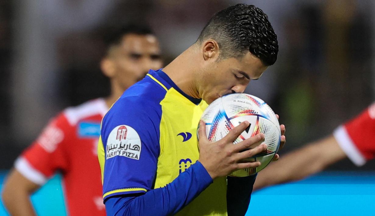 <p>Pemain Al Nassr, Cristiano Ronaldo mencium bola sebelum menendang bola dari titik penalti ke gawang Al Wehda yang membuahkan gol dalam pertandingan lanjutan pekan ke-16 Liga Arab Saudi 2022/2023 yang berlangsung di King Abdulaziz Sports City Stadium, Jumat (10/2/2023) WIB. Kini Ronaldo telah mengemas lima gol dari empat pertandingannya bersama Al Nassr. (AFP)</p>