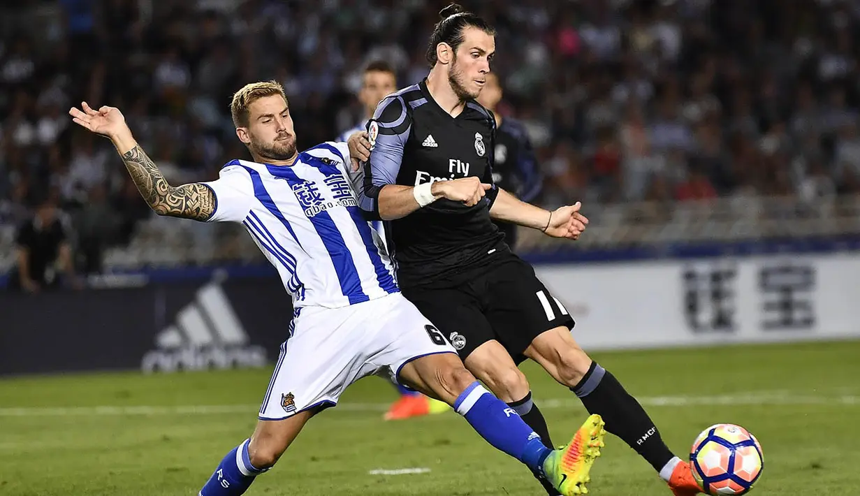 Pemain Real Madrid, Gareth Bale, berusaha melewati pemain Real Sociedad, Inigo Martinez. Bale berhasil mencetak dua gol kemenangan Los Blancos yang dibukukannya pada menit ke-2 dan 90+4. (AP/Alvaro Barrientos)