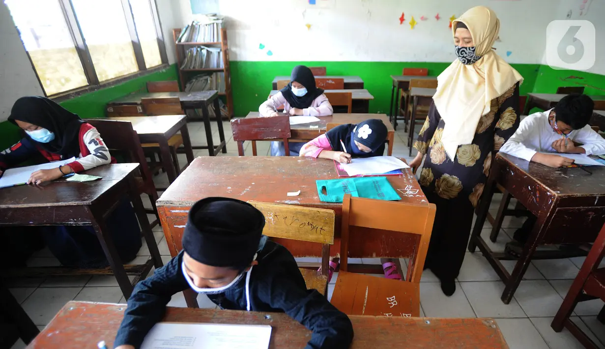 Guru mengawasi murid kelas V saat menjalani ujian Penilaian Akhir Semester (PAS) tahun pelajaran 2020/2021 di Madrasah Ibtidayah (MI) Assu'ada di Pancoran Mas, Depok, Jawa Barat, Selasa (1/12/2020). Ujian dilaksanakan dengan menerapkan protokol kesehatan dalam kelas. (merdeka.com/Arie Basuki)