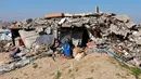 Menurut Trump, Dewan Perdamaian Gaza dirancang untuk mengawasi pembentukan pemerintahan teknokrat Palestina yang masih akan dibentuk, sekaligus memantau proses rekonstruksi di Jalur Gaza. Tampak dalam foto, para pengungsi Palestina hidup di tengah reruntuhan rumah dan bangunan yang hancur akibat serangan militer Israel selama lebih dari dua tahun di wilayah Gaza, di kamp pengungsi Jabalia, di bagian utara Jalur Gaza pada Sabtu 17 Januari 2026. (Omar AL-QATTAA/AFP)