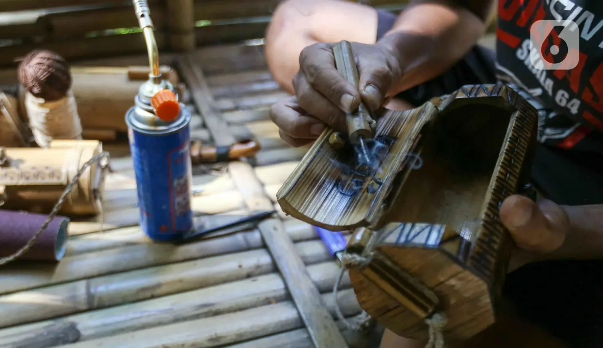 Perajin membuat kerajinan tas dari limbah bambu di Grand Depok City, Depok, Jawa Barat, Kamis (2/6/2022). Komunitas Ciliwung Depok (KCD) memanfaatkan limbah bambu yang berada di Sungai Ciliwung menjadi kerajinan seperti tas, tempat alat tulis, dan cangkir. (Liputan6.com/Herman Zakharia)