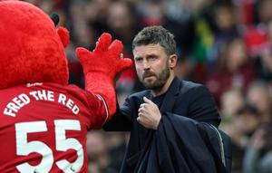Pelatih sementara Manchester United asal Inggris, Michael Carrick (kanan), bertepuk tangan dengan maskot Fred the Red menjelang dimulainya pertandingan Liga Inggris antara Manchester United dan Brentford di Old Trafford, Manchester, barat laut Inggris, pada 28 April 2026. (Darren Staples/AFP)