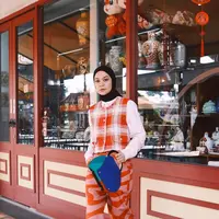 Gaya Tantri Namirah tak pernah gagal memesona. Di sini ia mengenakan kemeja putih ditumpuknya dengan vest bermotif kotak-kotak oranye putih, dan dipadukan dengan celana panjang bermotif abstrak yang senada. Ia memamerkan tas birunya yang kontras, dengan hijab hitam dan sneakers putih yang edgy. [Foto: Instagram/tantrinamirah]