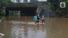 Warga berjalan kaki melintasi kawasan DI Panjaitan, Jakarta, Selasa (25/2/2020). Hujan yang mengguyur Jakarta sejak dini hari tadi membuat kawasan tersebut terendam banjir sehingga tak bisa dilintasi kendaraan bermotor. (Liputan6.com/Herman Zakharia)