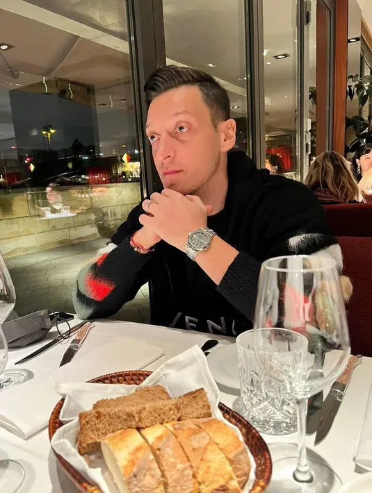 <p>Terlihat berpose di meja makan, Mezut Ozil terlihat rapi mengenakan hoodie hitam dengan boost huruf-huruf berwarna abu-abu. Foto: Instagram.</p>