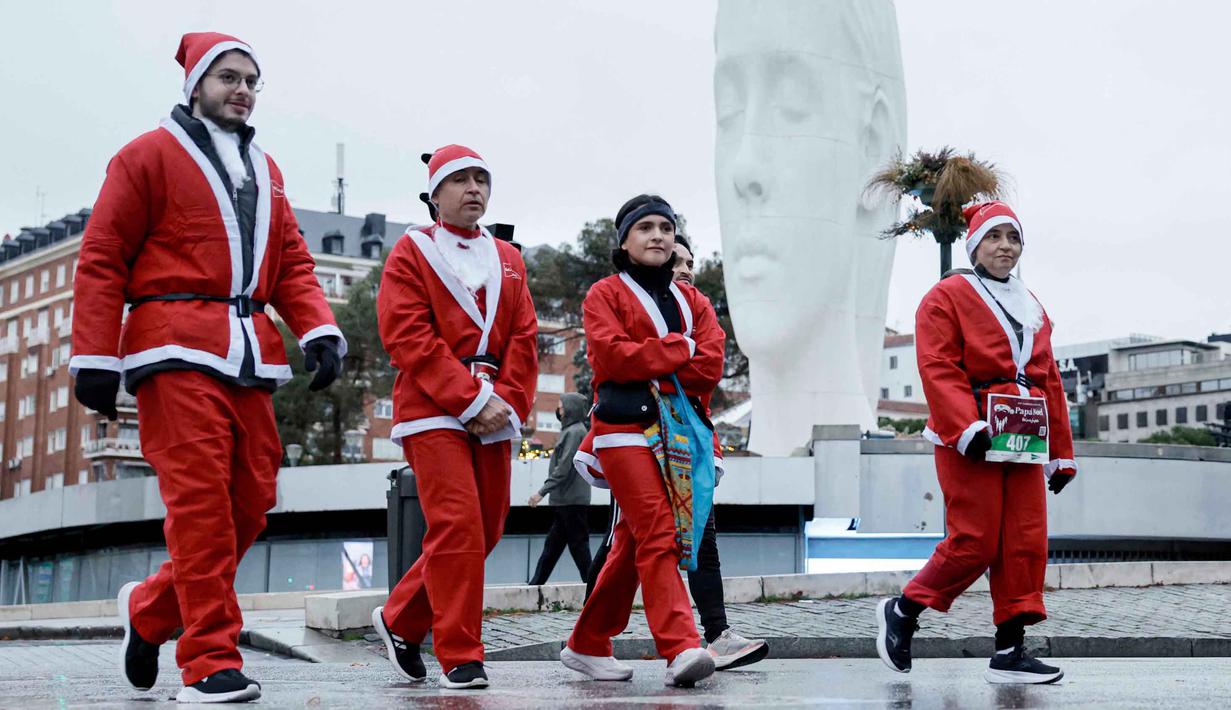 Tahun ini menjadi yang ke-14 kalinya ajang ini diselenggarakan. Tampak dalam foto, orang-orang yang mengenakan kostum Santa Claus sesaat sebelum berpartisipasi dalam edisi ke-14 lomba Santa Claus, sebuah lari santai sejauh 4,5 km melalui jalan-jalan Madrid pada Minggu 21 Desember 2025. (OSCAR DEL POZO/AFP)