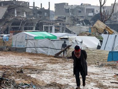 Seorang pria Palestina berjalan di depan tenda-tenda yang didirikan di tengah kehancuran di Beit Hanoun, Jalur Gaza utara pada 12 Februari 2025. (Omar AL-QATTAA/AFP)