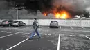 Seorang prajurit Ukraina berjalan melewati saat api dan asap membubung di atas pusat logistik yang rusak setelah penembakan di Kyiv, Ukraina, Kamis (3/3/2022). Rusia telah meluncurkan serangan jarak jauh ke Ukraina, menghantam kota dan pangkalan dengan serangan udara atau penembakan. (AP Photo/Efrem