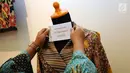 Petugas memasang tulisan di baju batik milik Sri Mulyani yang akan dilelang pada lelang sukarela di Galeri Nasional, Jakarta, Selasa (27/2). Lelang barang pribadi itu merupakan peringatan 110 tahun Lelang Indonesia. (Liputan6.com/Helmi Fithriansyah)