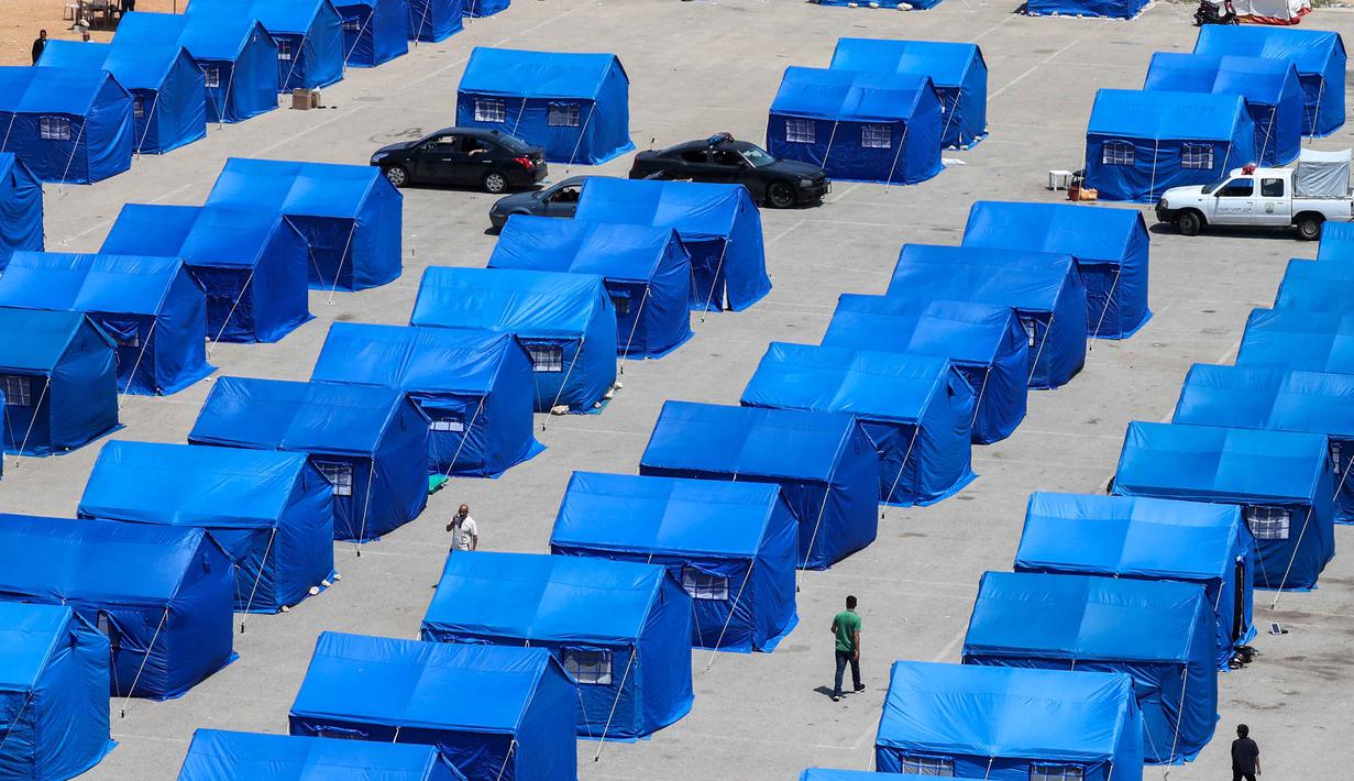 Warga Lebanon yang mengungsi berjalan di antara tenda-tenda biru yang didirikan pemerintah untuk orang-orang yang meninggalkan rumah dan desa mereka di pinggiran selatan Beirut dan Lebanon Selatan, Jumat 22 Mei 2026. (Anwar AMRO/AFP)