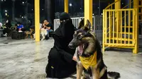 Seorang perempuan duduk dengan anjing herdernya di kafe "Barking Lot" di kota pesisir Khobar, Arab Saudi,  25 September 2020. Pemilik anjing di Arab Saudi kini dapat menikmati secangkir kopi bersama hewan kesayangan di kafe baru, sekaligus yang pertama di negara konservatif itu (FAYEZ NURELDINE/AFP)