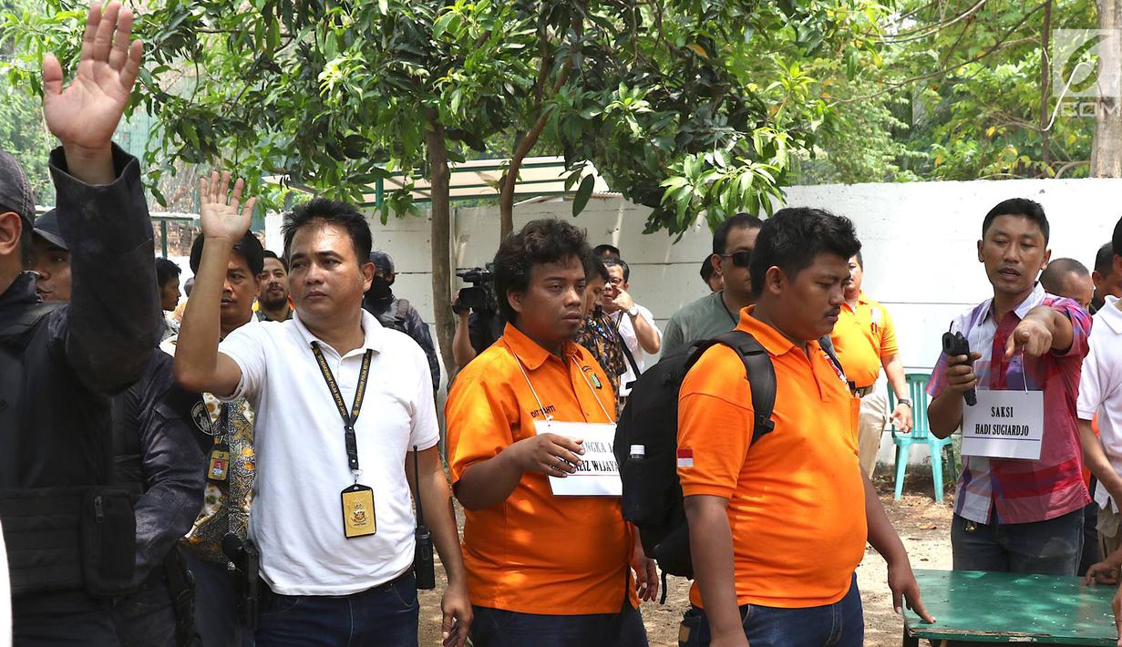 Tersangka IAW menjalani proses rekonstruksi Lapangan Tembak Senayan, Jakarta, Jumat (19/10). IAW menjalani 25 adegan rekonstruksi terkait dugaan enam peluru yang tertembak ke enam ruangan di Gedung DPR RI. (Liputan6.com/Immanuel Antonius)