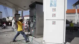 Pengunjuk mencoba menghancurkan tangki pom bensin saat demo pemilu di Port-au-Prince, Haiti (18/1). Warga menuduh pemilu presiden Haiti berjalan curang yang menyebabkan kemarahan warga hingga membakar fasilitas umum. (REUTERS/Andres Martinez Casares)