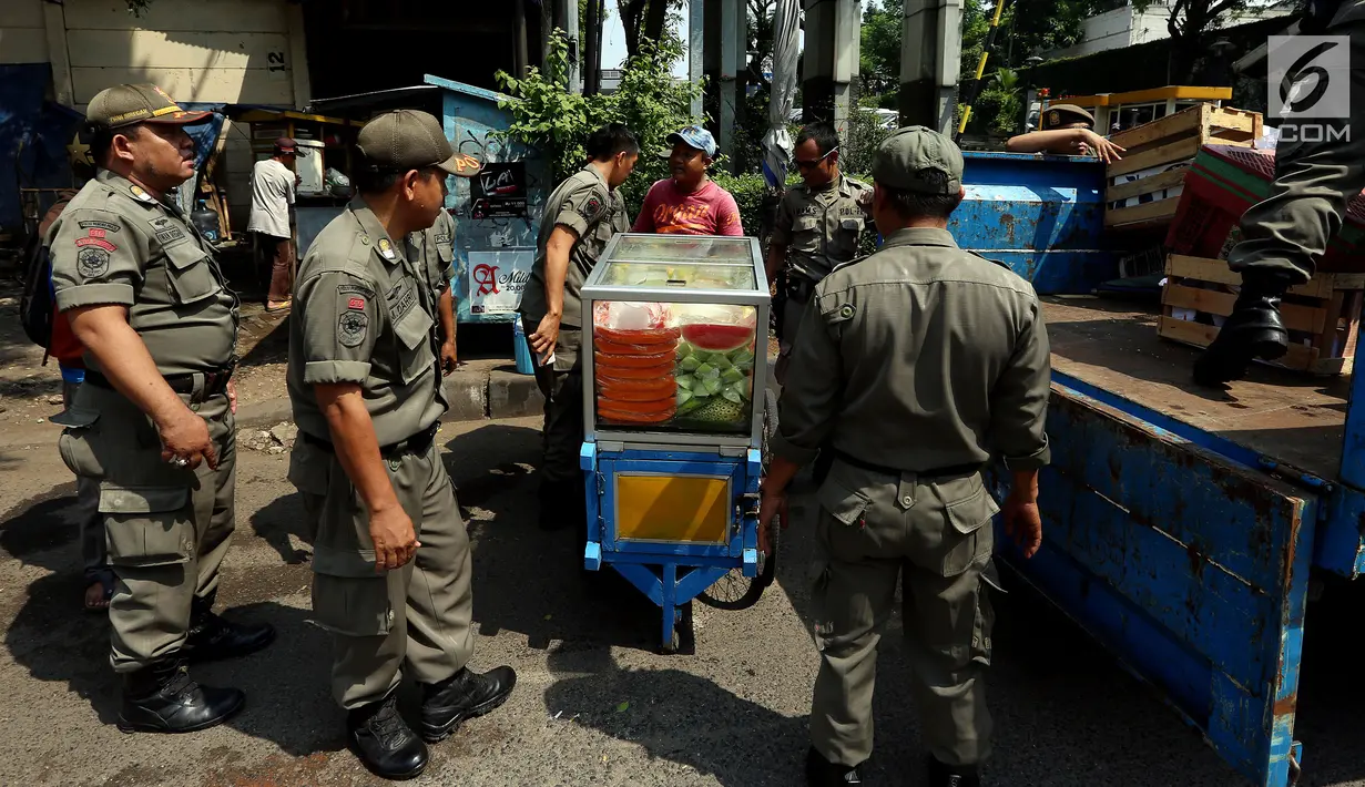 Pedagang buah keliling terkena razia yang dilakukan oleh Satpol PP di kawasan Karet, Jakarta, Senin (17/7). Tindakan razia tersebut untuk membuat jera pedagang kaki lima yang nakal dan tetap nekat berjualan di bahu jalan. (Liputan6.com/Johan Tallo)