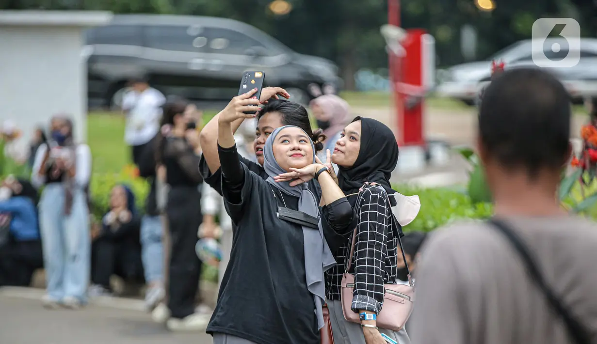 Penonton berselfie saat antre memasuki gerbang konser Dream Perfect Regime (DPR) di Jakarta, Selasa (6/12/2022). Dream Perfect Regime atau biasa dikenal dengan DPR adalah label musik dan video independen multi-genre yang dibentuk pada akhir tahun 2015. (Liputan6.com/Faizal Fanani)
