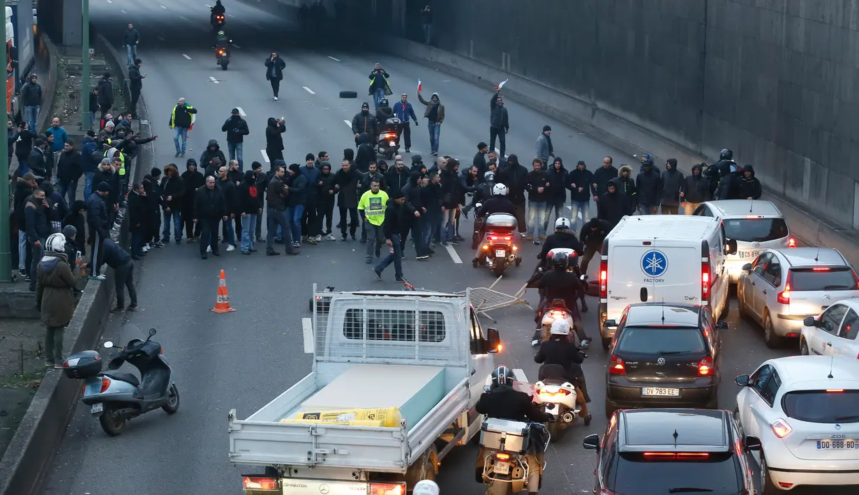Sopir taksi memblokir jalan saat unjuk rasa menentang layanan transportasi VTC seperti Uber, di jalan lingkar di porte Maillot di Paris, Perancis, Selasa (26/1). (AFP PHOTO/Thomas SAMSON)