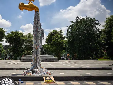Instalasi berbentuk keran yang mengalirkan botol plastik terlihat dalam sebuah aksi protes yang dilakukan oleh para aktivis dari Ecological Observation and Wetlands Conservation (ECOTON) dan para mahasiswa di Surabaya, Jawa Timur, Selasa 25 Februari 2025. (Juni KRISWANTO/AFP)